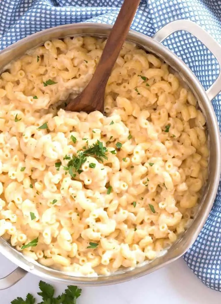 Macaroni and cheese in a big pot with a wooden spoon.