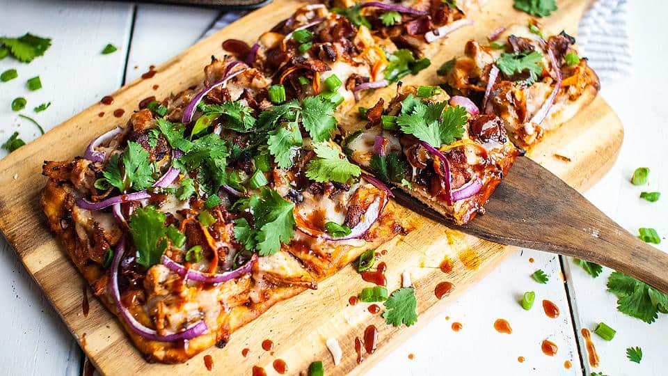 Bbq chicken pizza on a wooden cutting board.