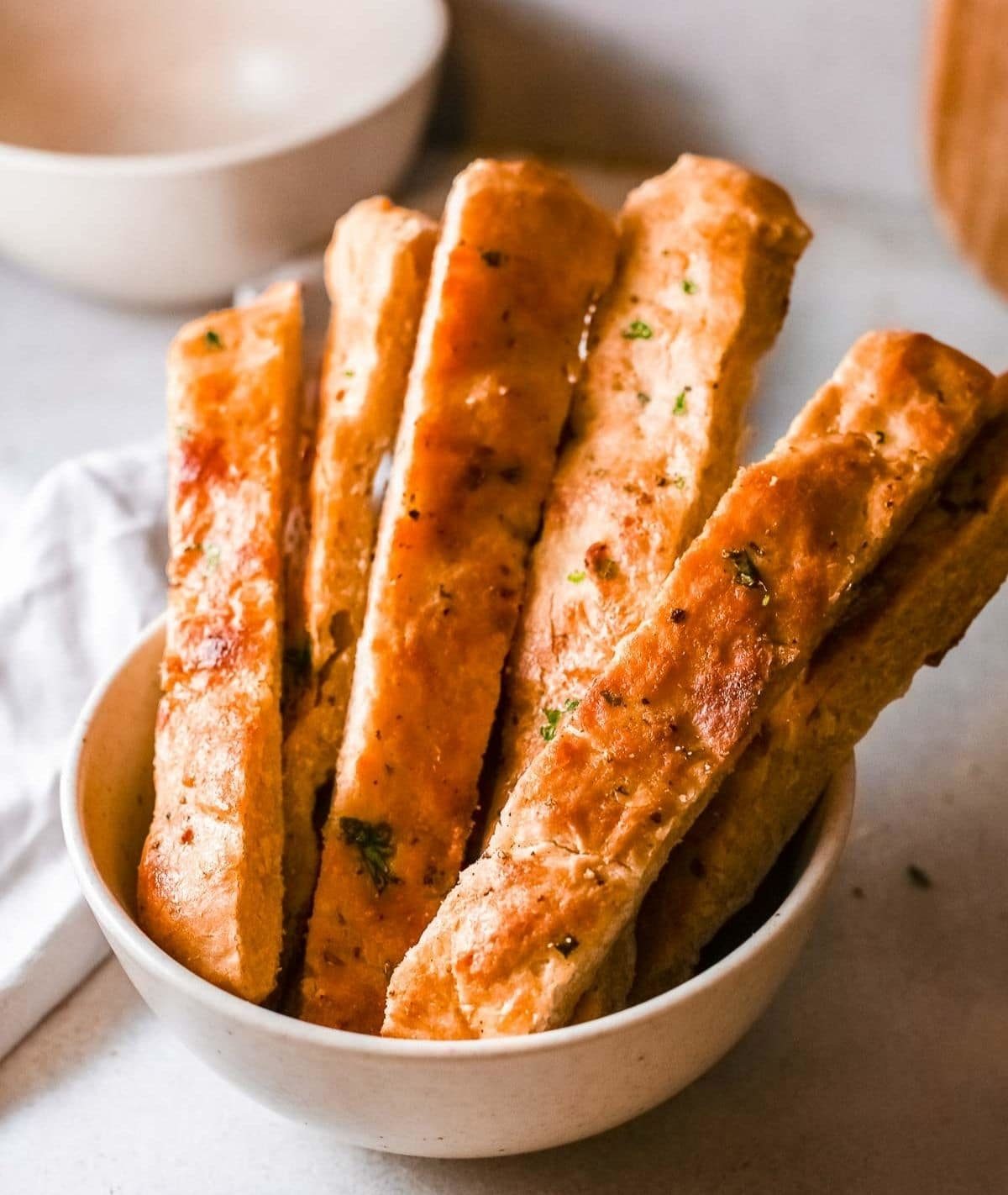 Garlic bread sticks in a white bowl.