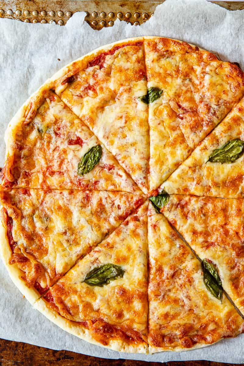 A whole cheese pizza on a piece of parchment paper.
