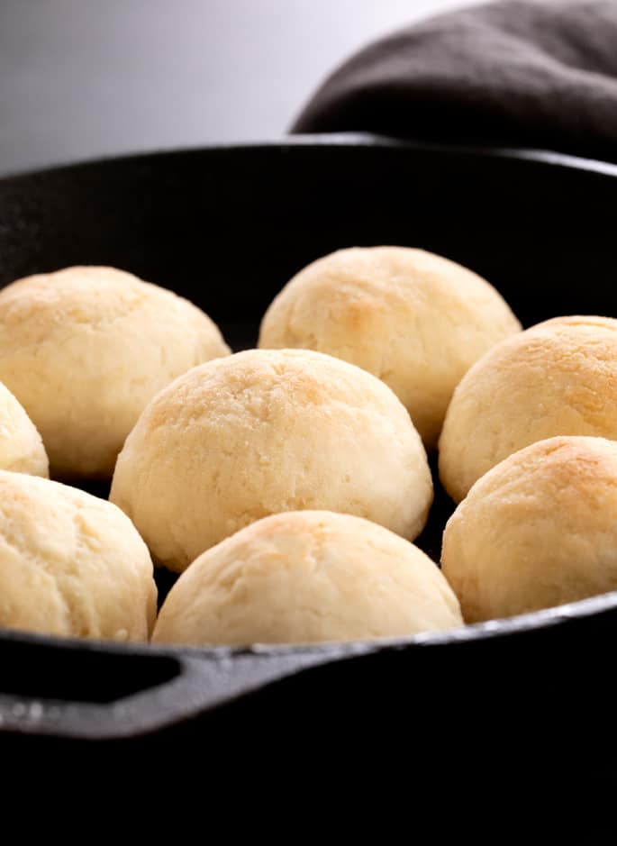 Yeast-free bread rolls sizzling in a skillet on a gray background.
