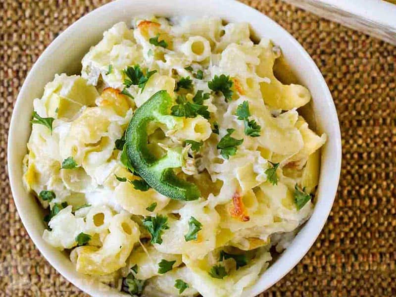 Cheesy artichoke dip mac and cheese in a white bowl.