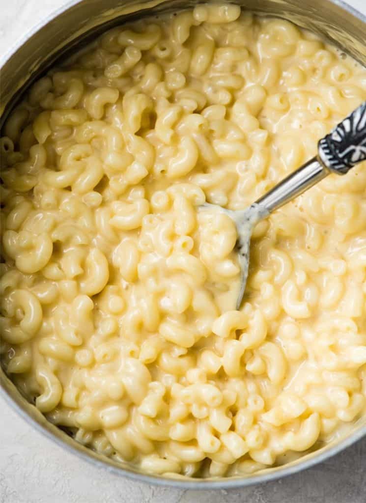 Homemade macaroni and cheese in a pot with a serving spoon.