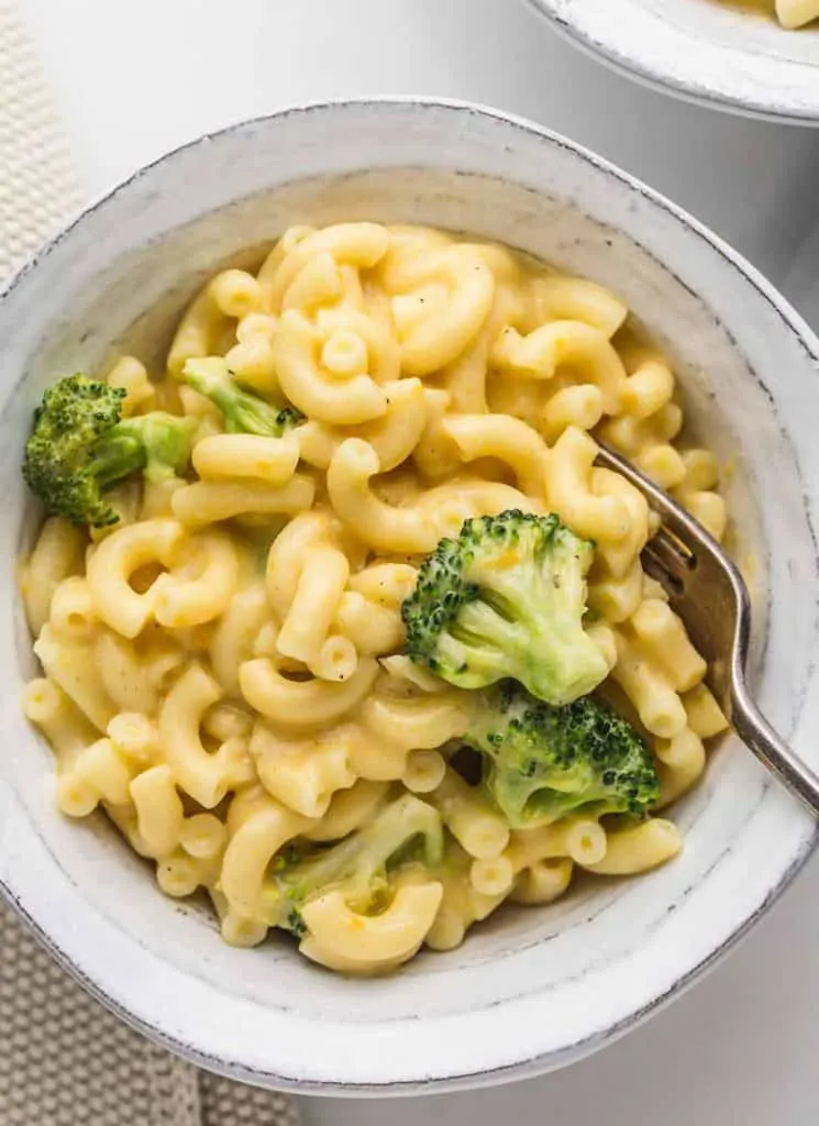 A bowl of macaroni and broccoli with a fork.