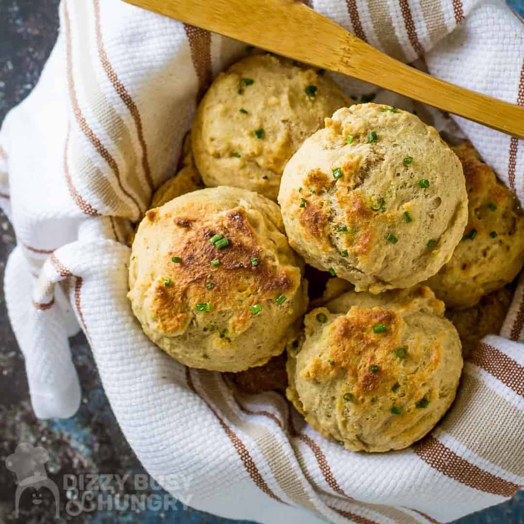 Homemade biscuits in a basket with a wooden spoon.