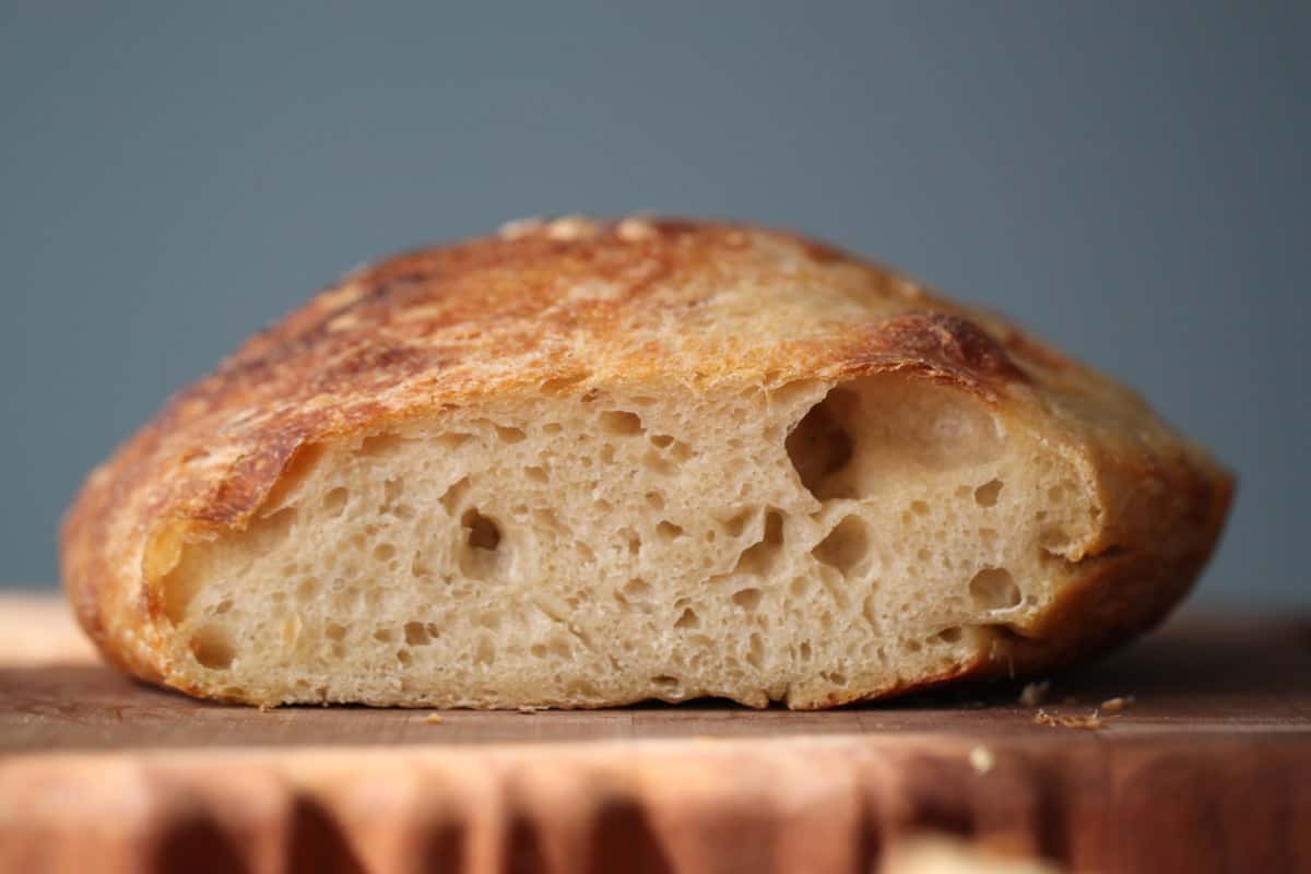 A loaf of no-knead bread on a rustic wooden cutting board.
