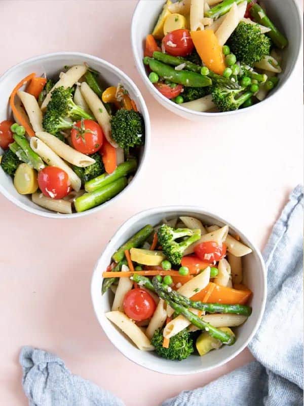 Three bowls of quick and easy pasta primavera with vegetables in them.