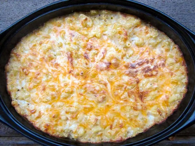 Quinoa mac and cheese in an oval black casserole dish.