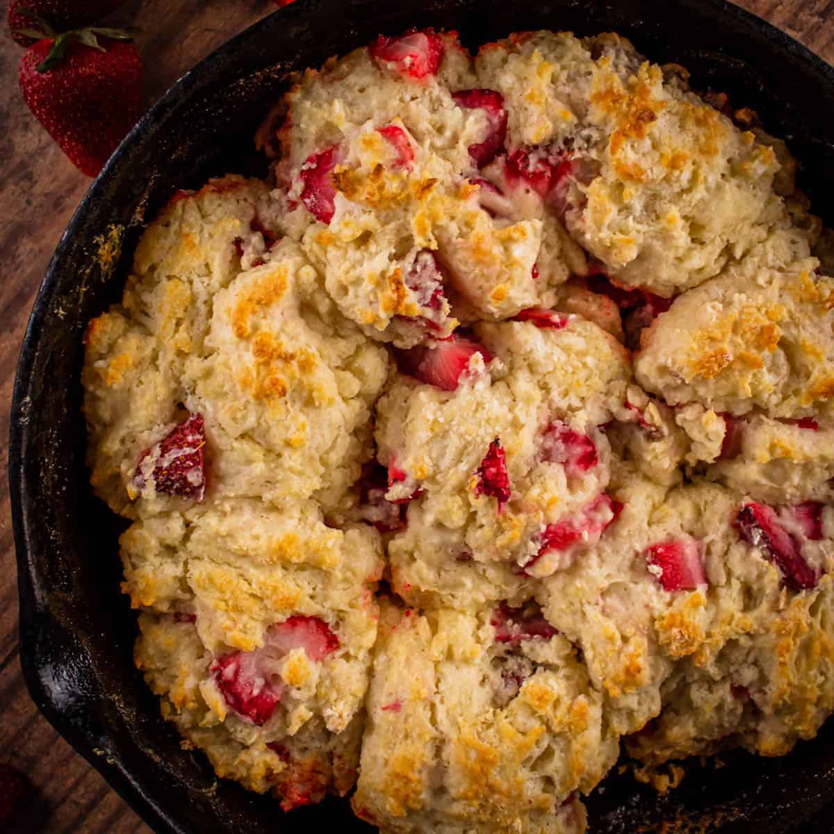 Strawberry scones in a skillet on a wooden table.