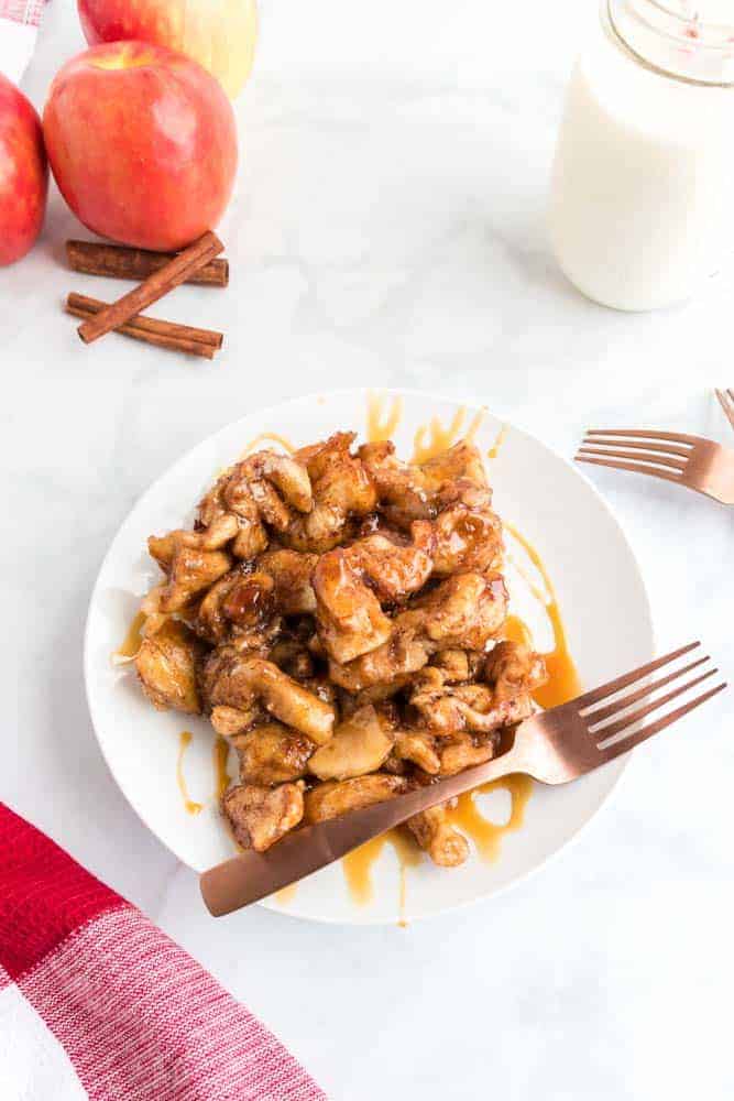 Apple pie cinnamon roll monkey bread in a white plate with a fork.