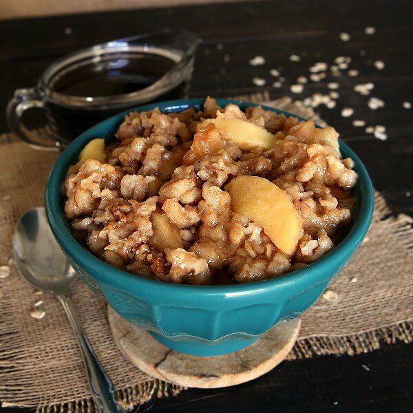 Apple oatmeal in a blue bowl next to a spoon.