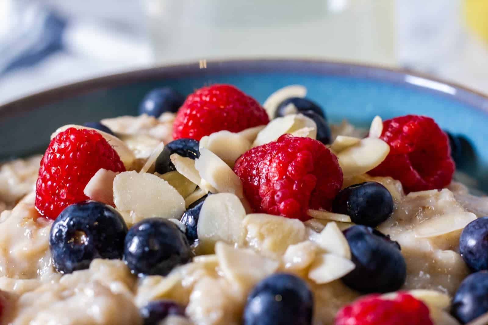 Slow cooker porridge garnished with raspberries, blueberries and sliced almonds.