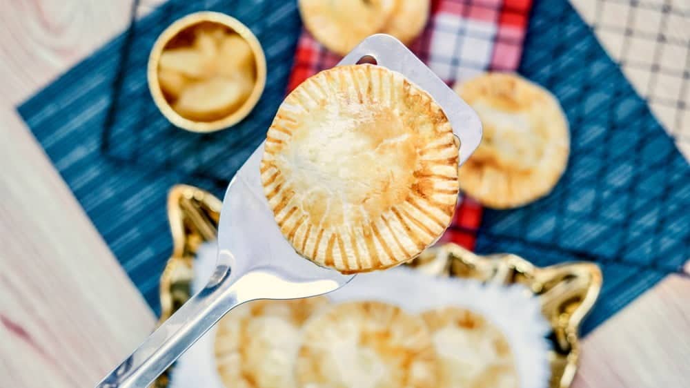 A piece of apple hand pie on a silver spatula.