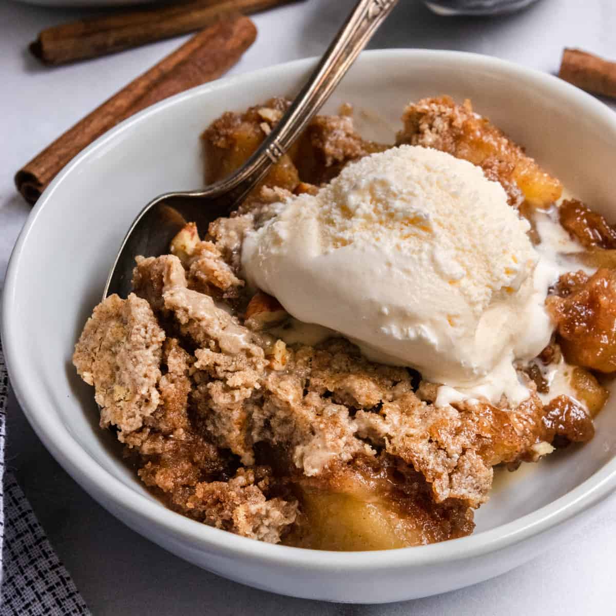Apple cake with vanilla ice cream topping in a bowl.