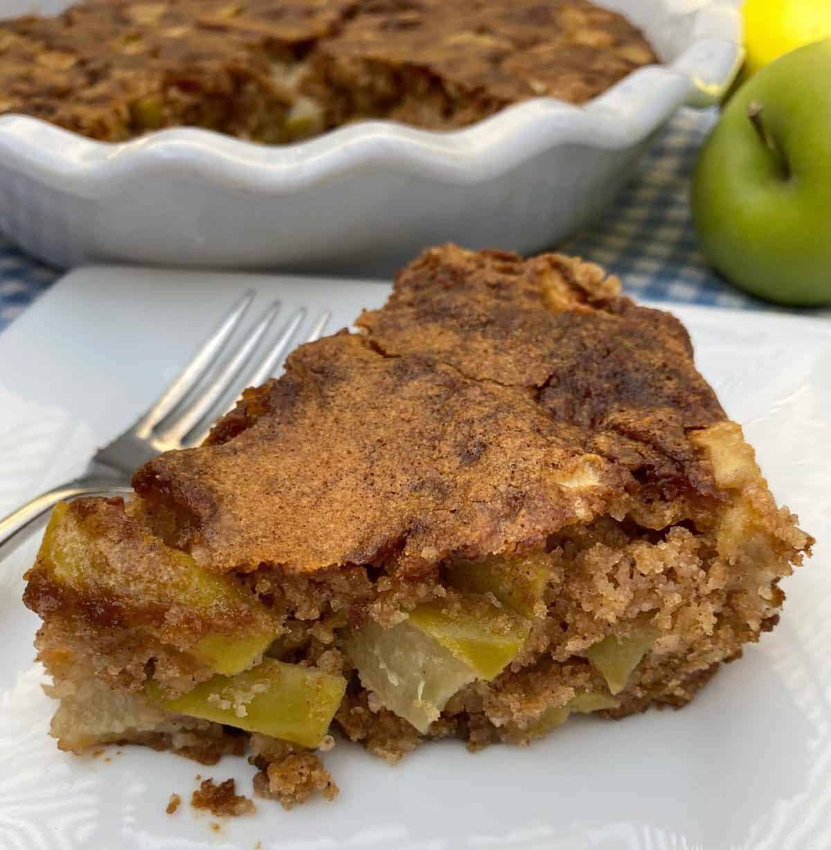 A slice of easy apple cake in a white plate with a fork.