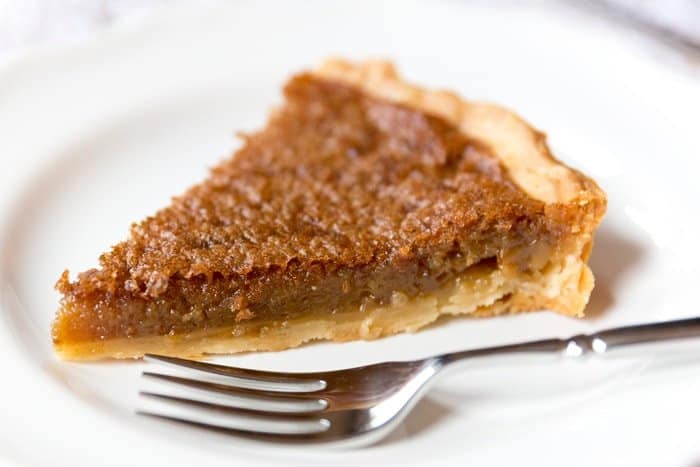 A slice of brown sugar pie in a plate with a fork.