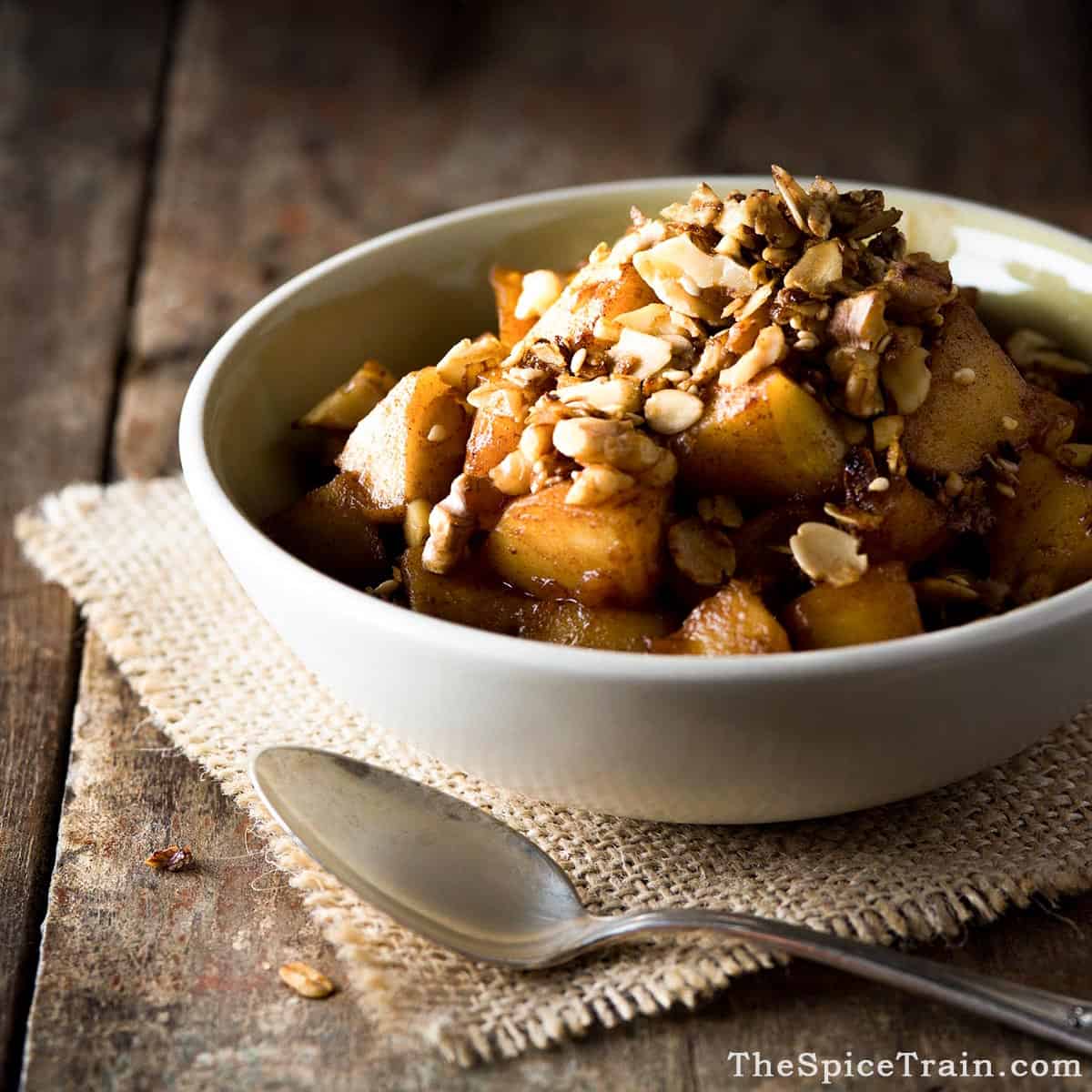 Stovetop apple crisp in a bowl next to a spoon.