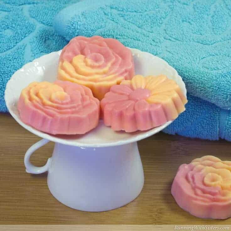 Flower-shaped pink and orange soap bars on white saucer with blue towel in the background.