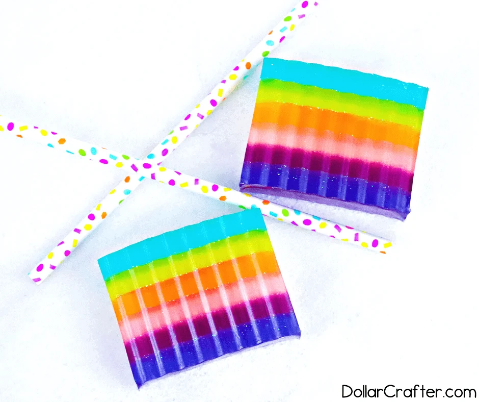 Two rainbow-colored soap bars next to two colorful paper straws.