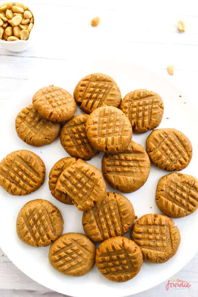 Peanut butter cookies on white plate with one cookie missing a bite.