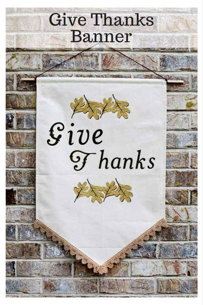 Give Thanks banner with gold fall leaves design hanging on a brick wall.