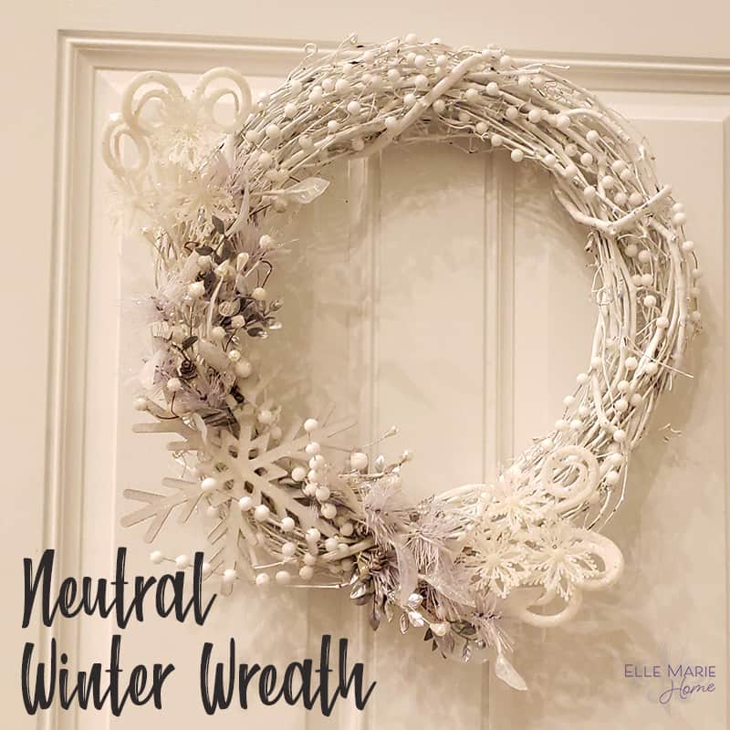 Neutral wreath designed with white berries and snowflakes hanging from a white door.