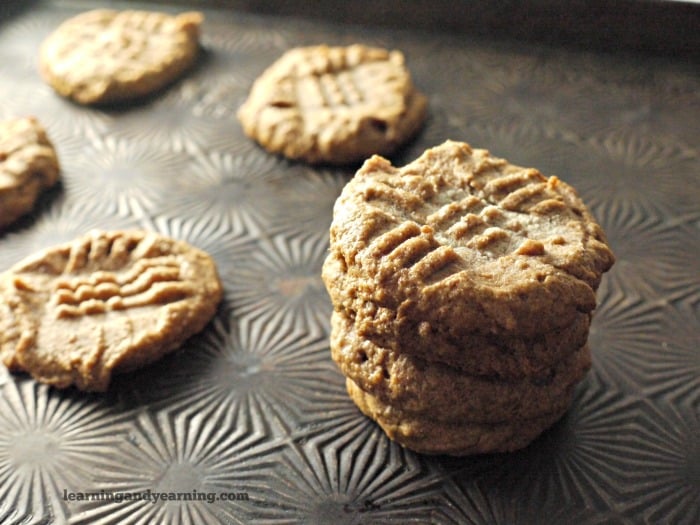 Four cookies stacked together next to four other cookies placed separately on a metal pan.