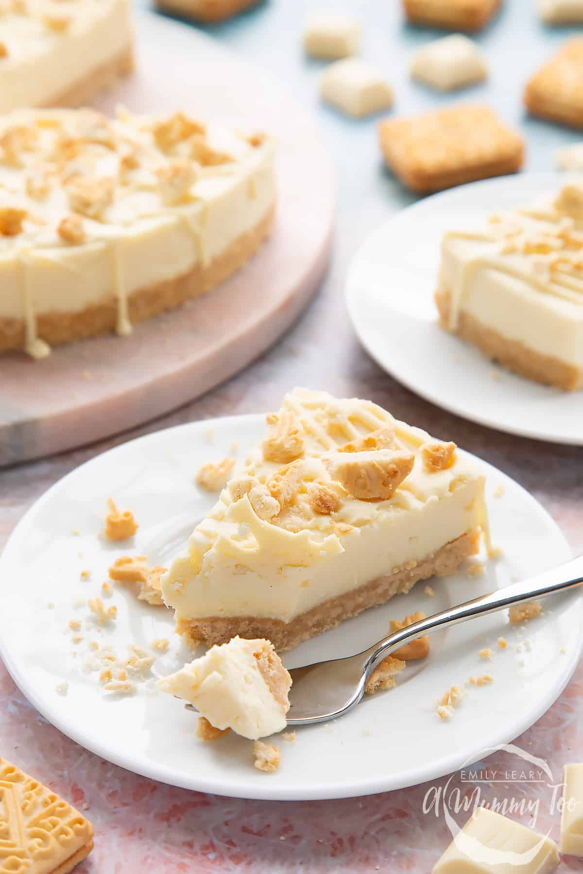 A slice of cheesecake on a white plate with a bite-size piece on a fork.