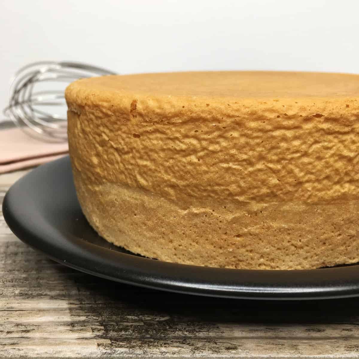 A close up photo of a sponge cake on a black plate.