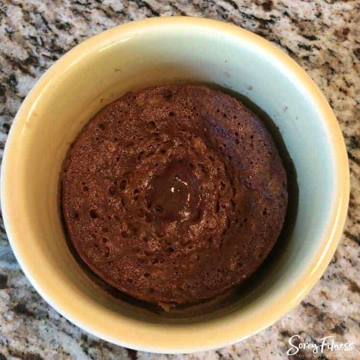 A chocolate cake in a mug with marble counter background.