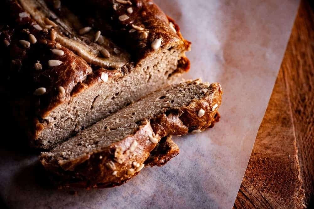 Close up photo of a whole banana bread with a slice on one end.