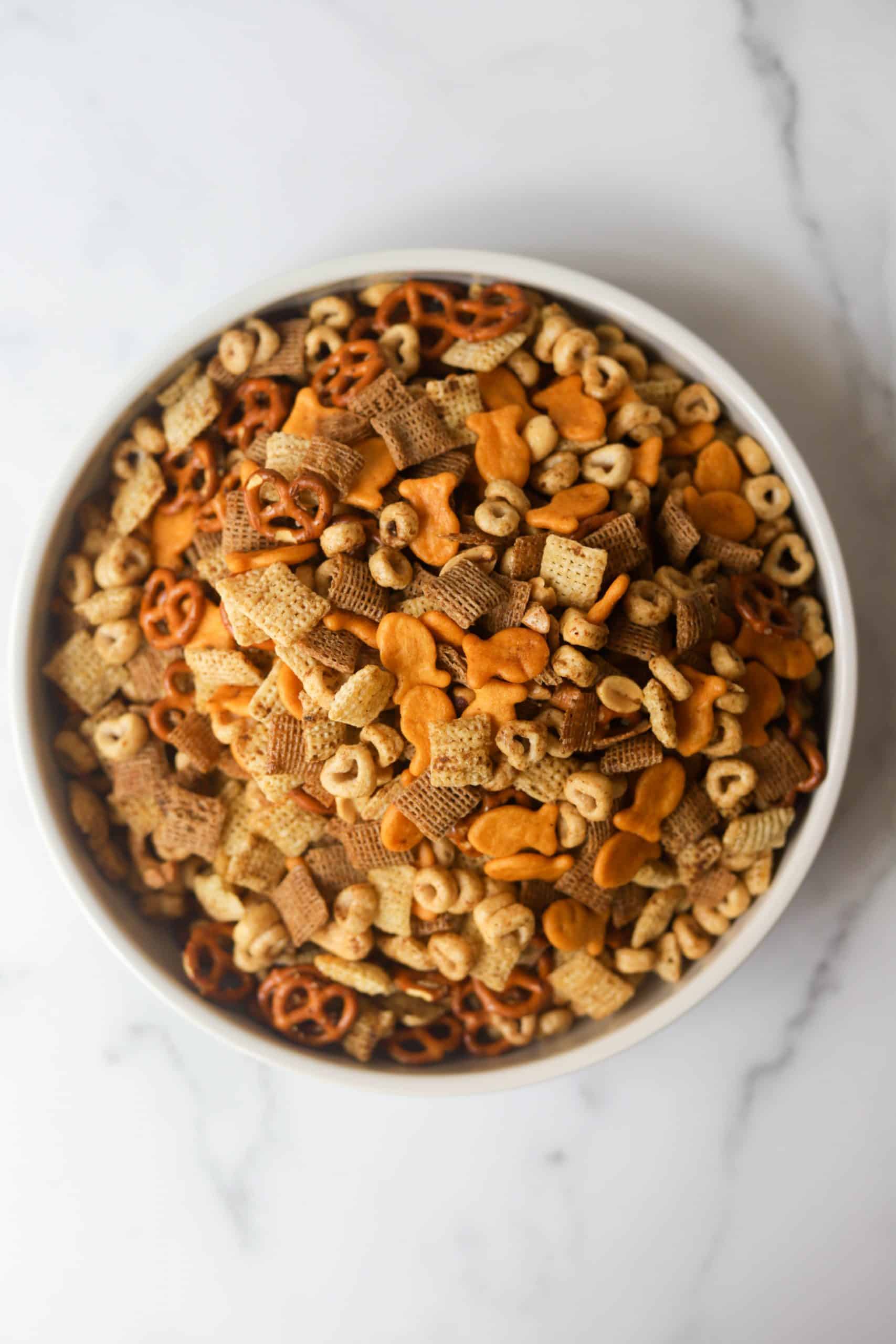 Healthy chex mix party snack with nuts in a white bowl.