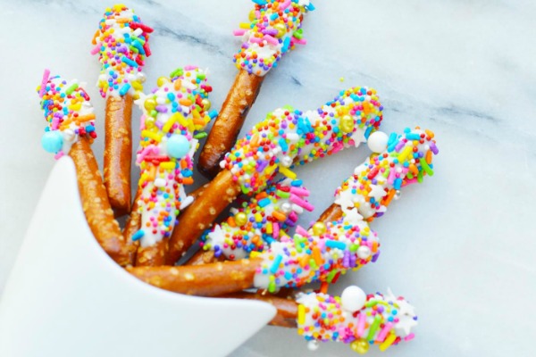 Unicorn horn pretzels snack covered with sprinkles in a white serving bowl.