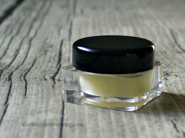 A small perfume jar with black lid.