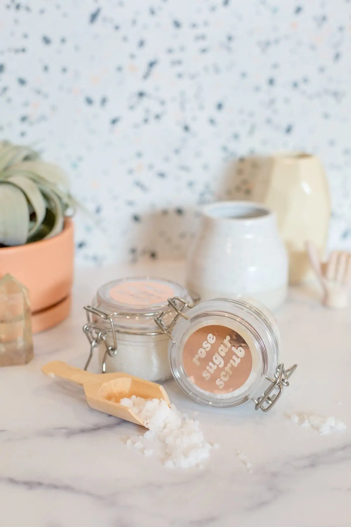 A jar of sea salt and a wooden spoon on a marble counter.