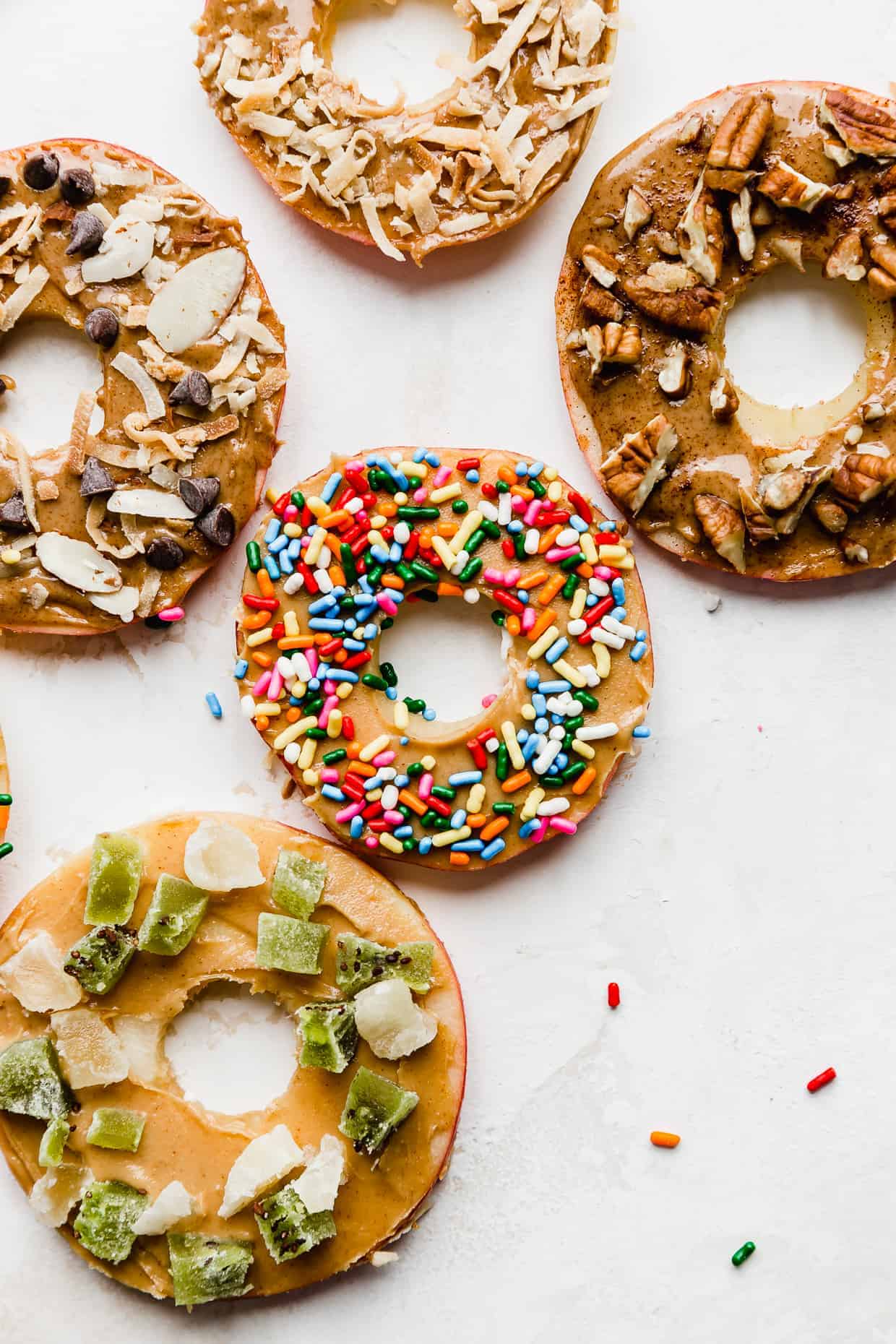Donut apples with sprinkles, nuts, chopped dried fruits and chocolate chips.