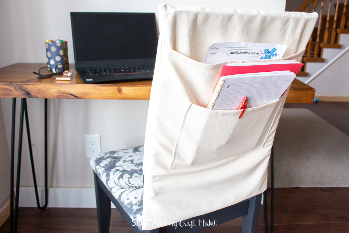 White student chair organizer with notebooks and papers. Chair facing the study table with a laptop on it.