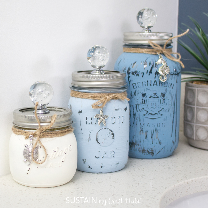 Three mason jars in different sizes with white, light blue and blue paint.