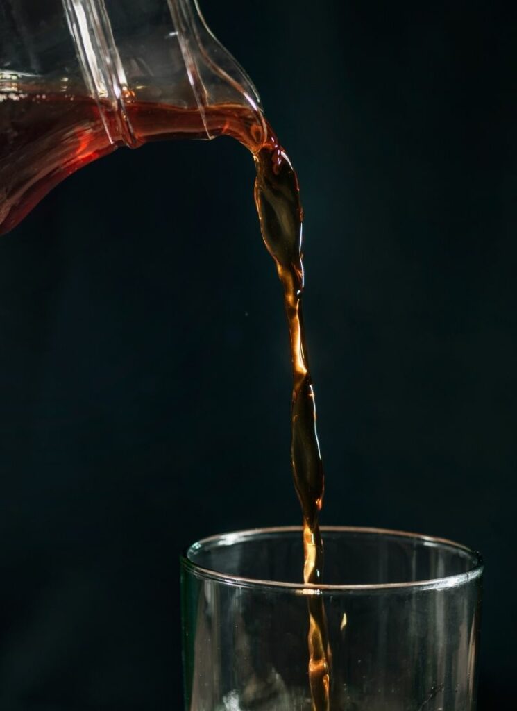 Close up photo of a coffee being poured into a glass.