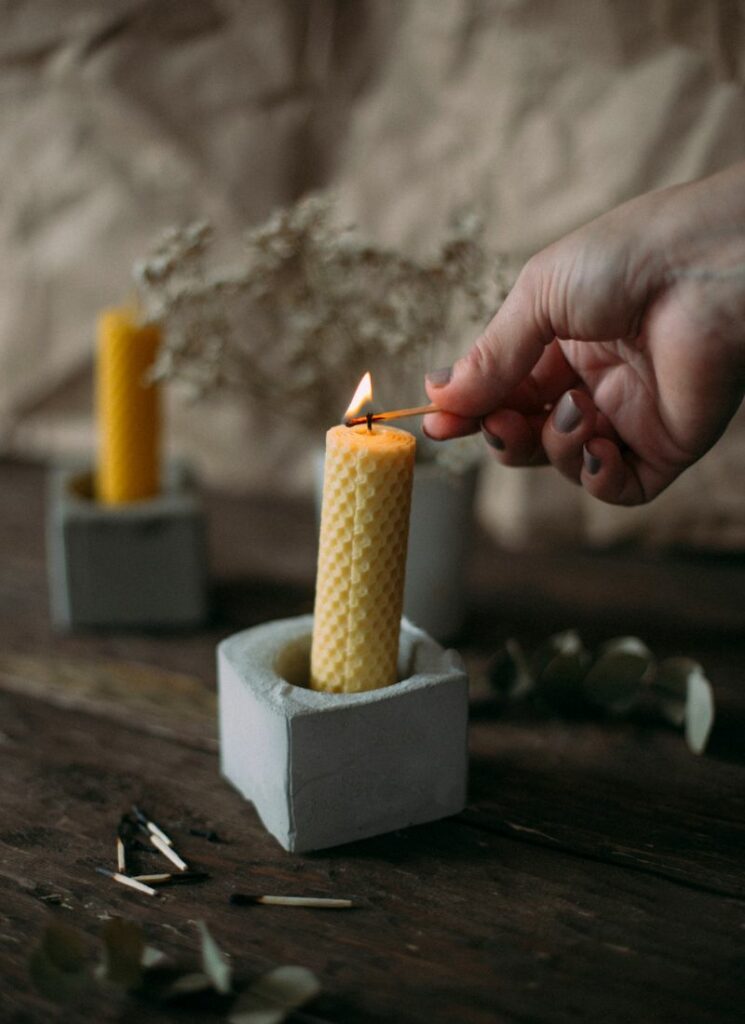 A person lighting a rolled beeswax candle.