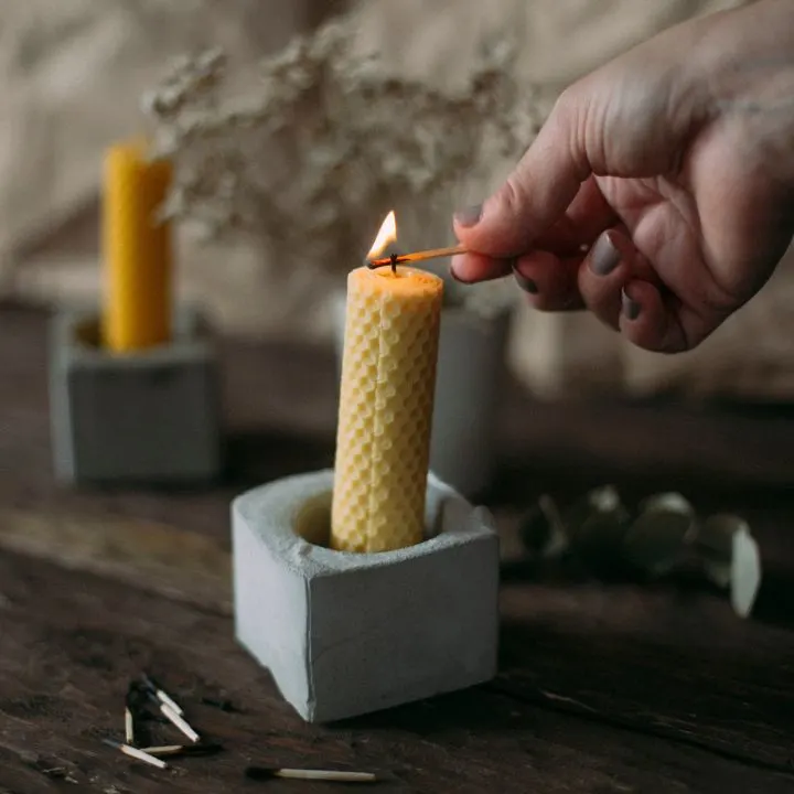 A person lighting a rolled beeswax candle.