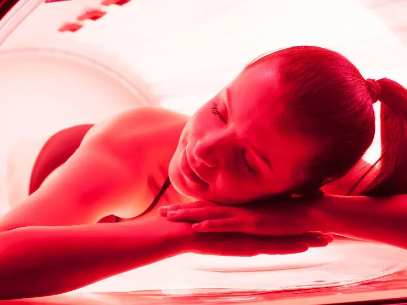 A woman lying down, tanning her back in a tanning bed.