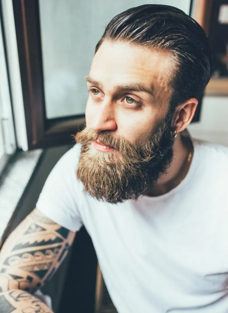 A man with a beard looking out of a window.