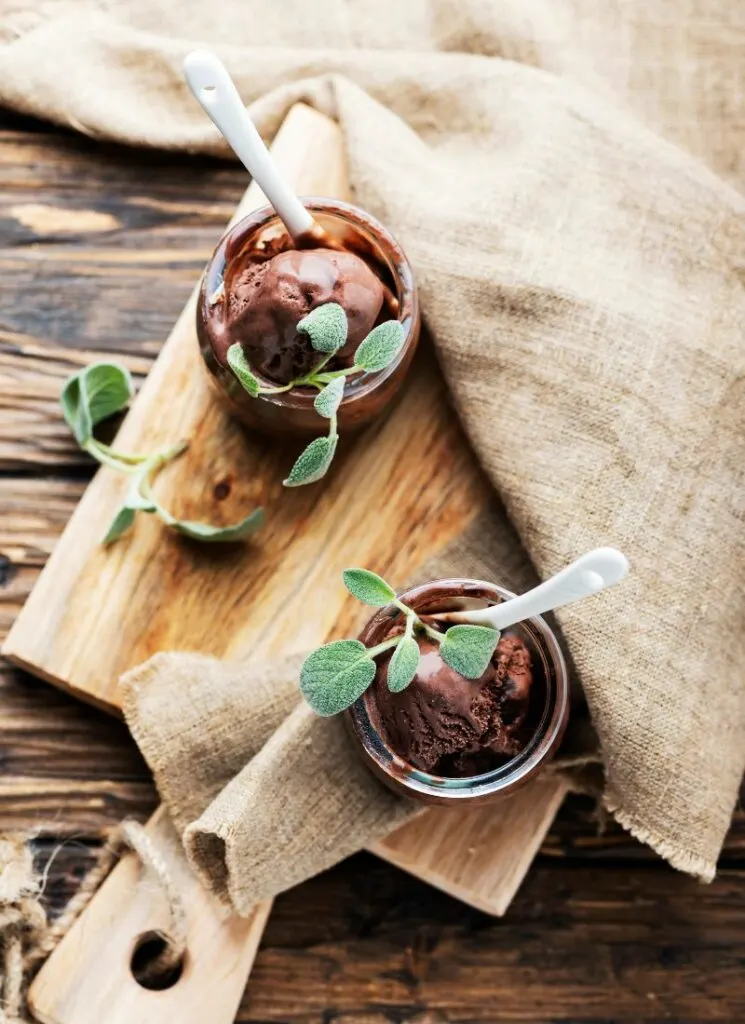 Two jars of chocolate sage ice cream with spoon.