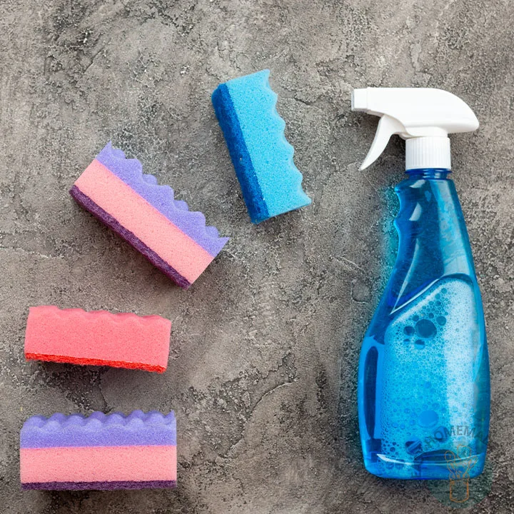 A blue spray bottle next to four sponges in different color.