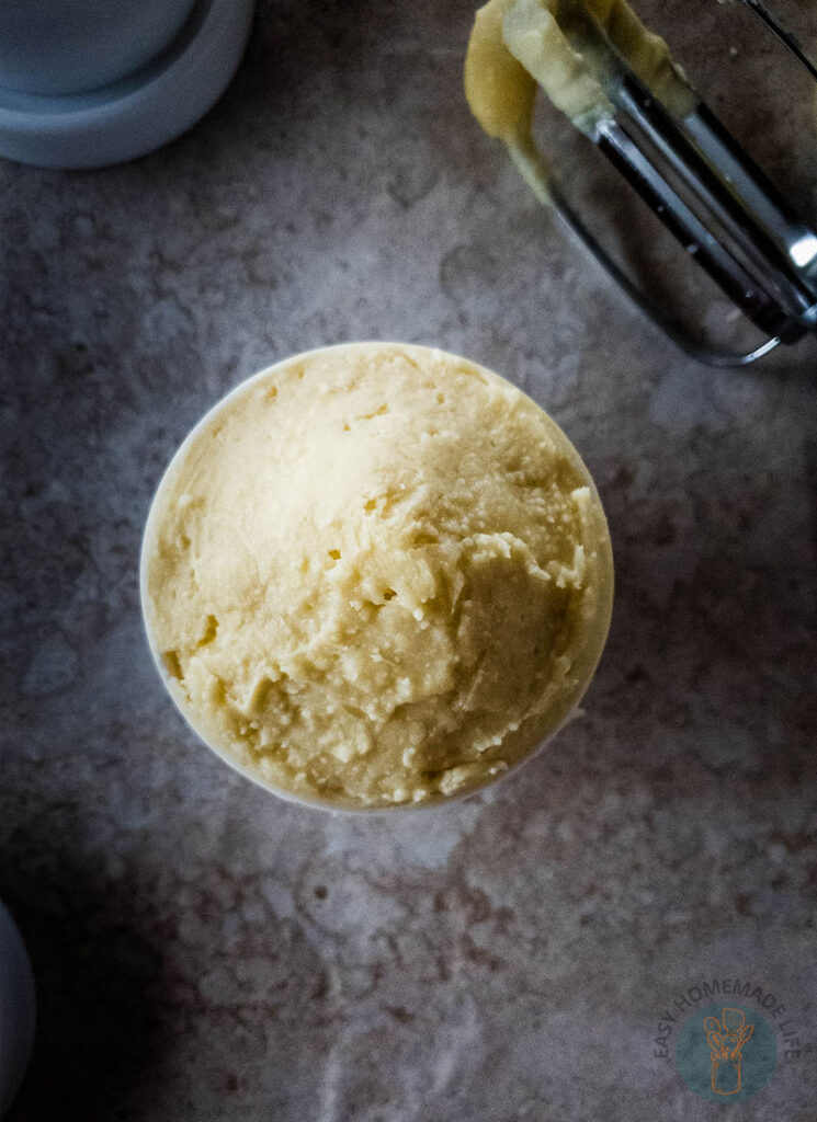 Beard butter in white container without lid next to a hand mixer.