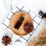 A wooden plate with pine cones and a bottle of woodsy essential oil blend.