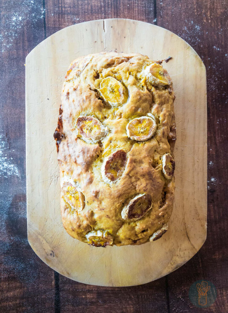 A whole banana bread on a wooden board.