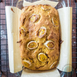 A whole banana bread in a parchment paper lined in a bread pan.