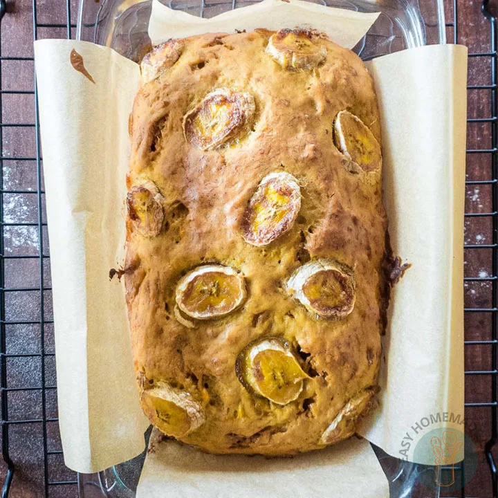 A whole banana bread in a parchment paper lined in a bread pan.